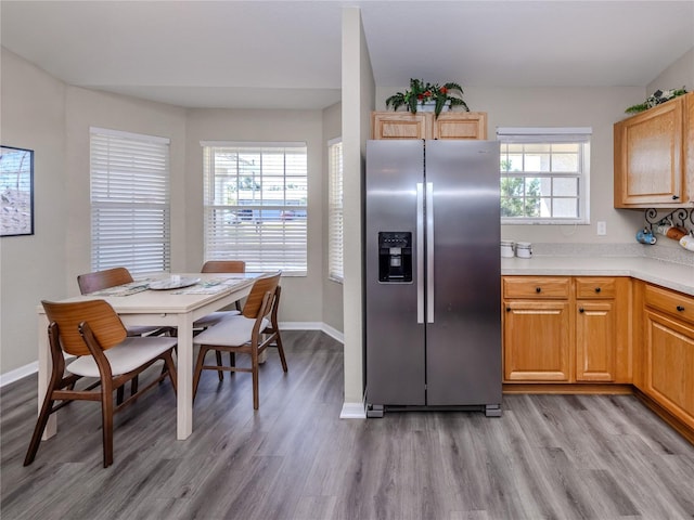 kitchen with light countertops, stainless steel fridge, light wood-style flooring, and baseboards