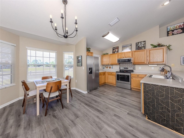 kitchen featuring a sink, vaulted ceiling, light countertops, appliances with stainless steel finishes, and light brown cabinetry