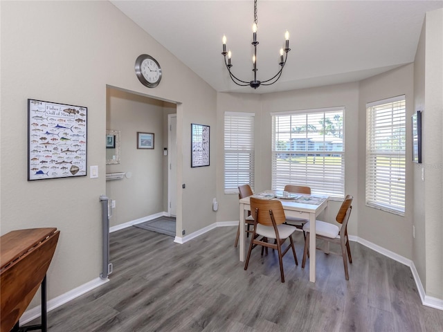 dining room with vaulted ceiling, an inviting chandelier, wood finished floors, and baseboards