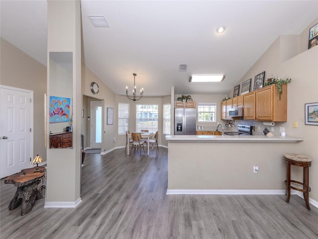 kitchen with a peninsula, visible vents, light countertops, appliances with stainless steel finishes, and light wood-type flooring