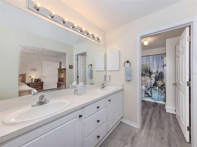 ensuite bathroom with wood finished floors, a sink, ensuite bath, and double vanity