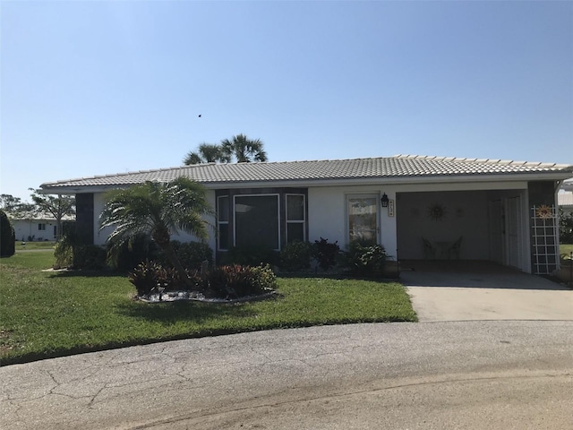 single story home with concrete driveway, a front yard, a tiled roof, and stucco siding