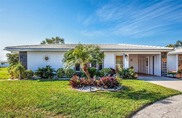 single story home with driveway, a tile roof, a front lawn, and stucco siding