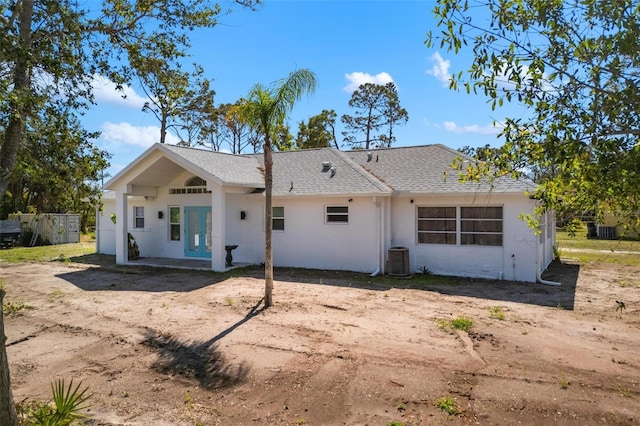 back of property featuring roof with shingles, stucco siding, and central air condition unit