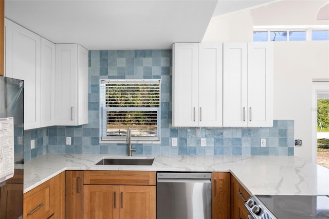 kitchen with stainless steel appliances, tasteful backsplash, a sink, and light stone countertops