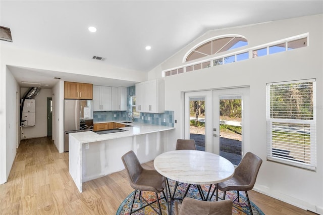 kitchen featuring a peninsula, visible vents, light countertops, freestanding refrigerator, and tasteful backsplash