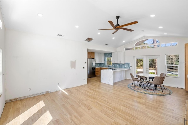 kitchen featuring a peninsula, visible vents, light countertops, light wood-type flooring, and freestanding refrigerator