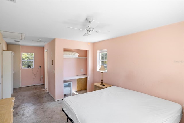 bedroom featuring attic access, multiple windows, concrete floors, and ceiling fan