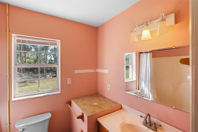 bathroom featuring curtained shower, plenty of natural light, vanity, and toilet