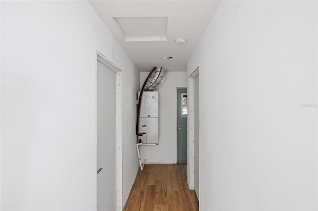 hall with attic access, water heater, and wood finished floors