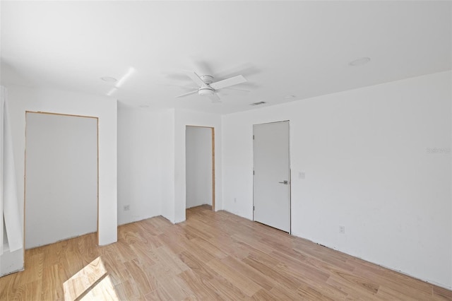 interior space featuring light wood-style flooring, a ceiling fan, and two closets