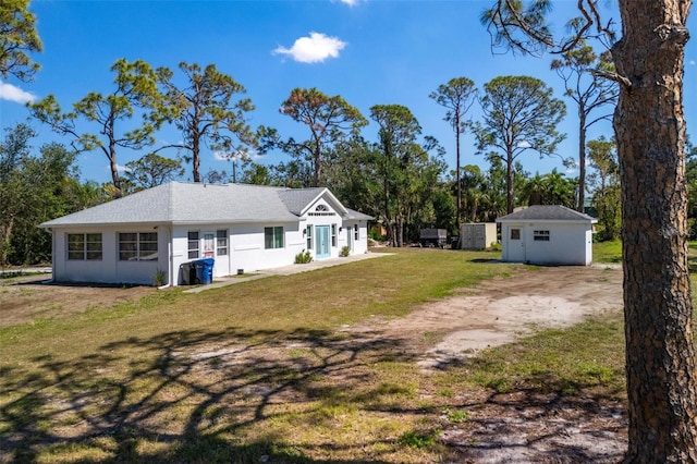 exterior space featuring an outbuilding, dirt driveway, a shed, and a lawn