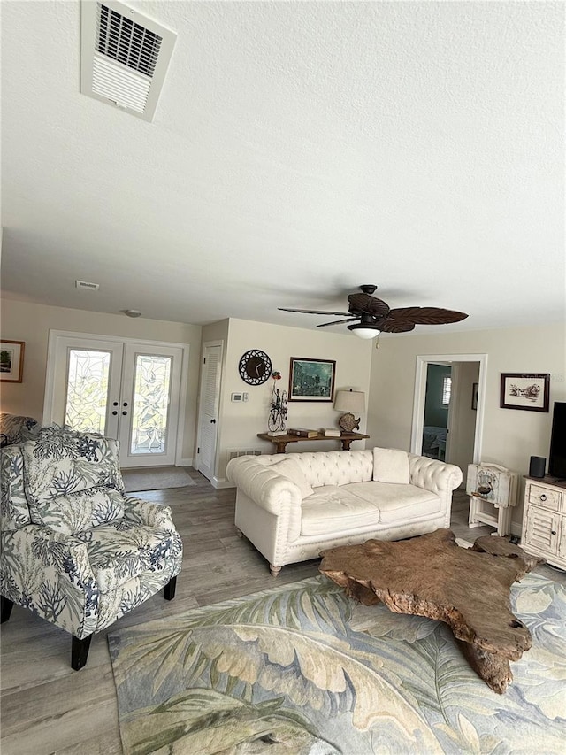 living area featuring a textured ceiling, french doors, wood finished floors, and visible vents