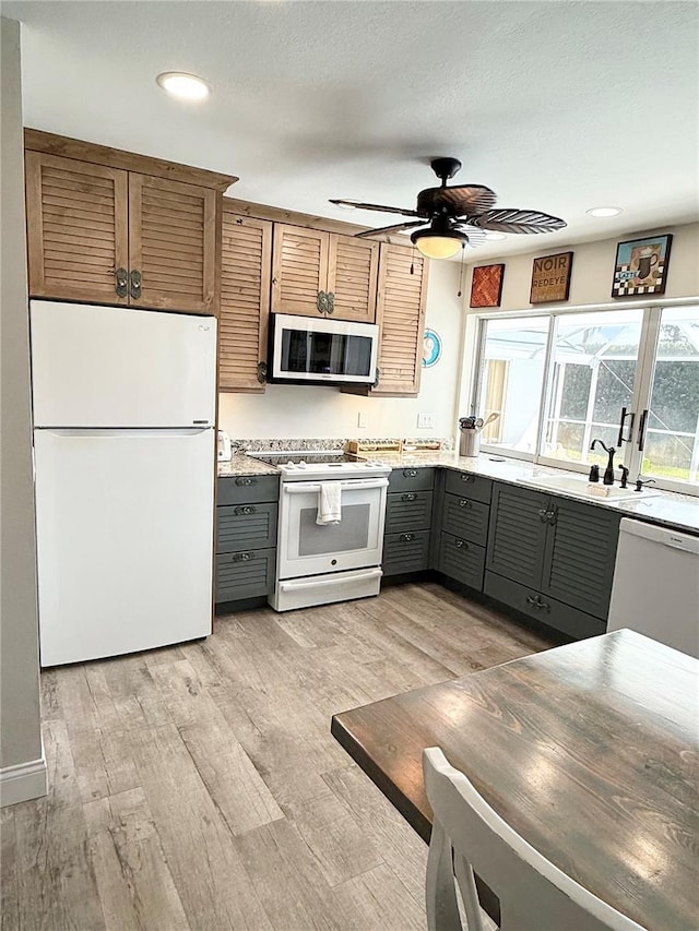 kitchen featuring white appliances, light wood-style flooring, ceiling fan, gray cabinetry, and a sink