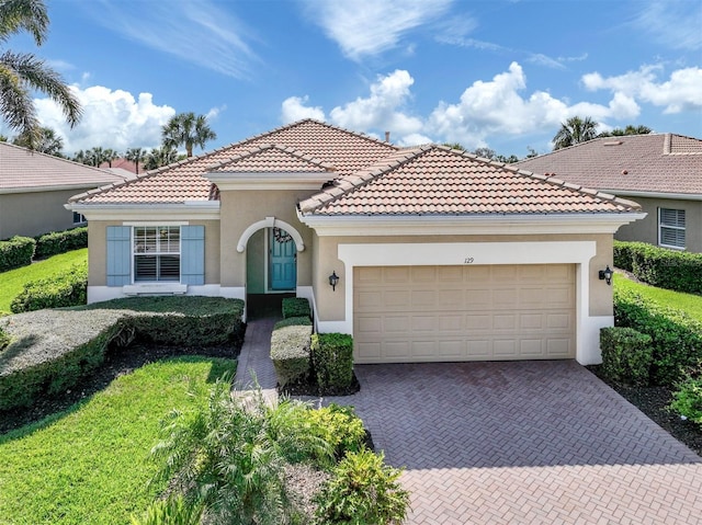 mediterranean / spanish-style home featuring a garage, decorative driveway, a tile roof, and stucco siding