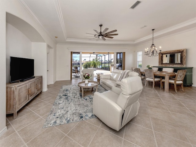 living room featuring light tile patterned floors, ceiling fan with notable chandelier, visible vents, a tray ceiling, and crown molding