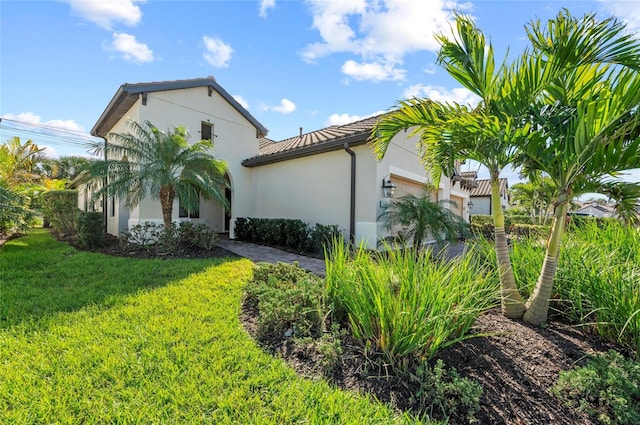 view of home's exterior featuring a garage, a yard, and stucco siding