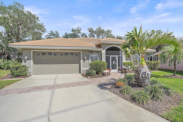 mediterranean / spanish-style house featuring a garage, concrete driveway, a tile roof, and stucco siding