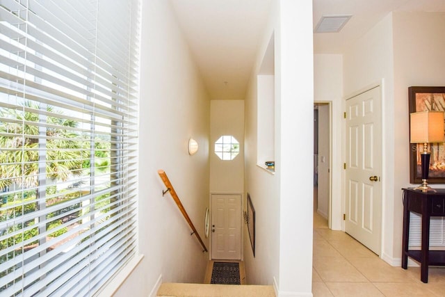 hall featuring visible vents, an upstairs landing, and light tile patterned floors