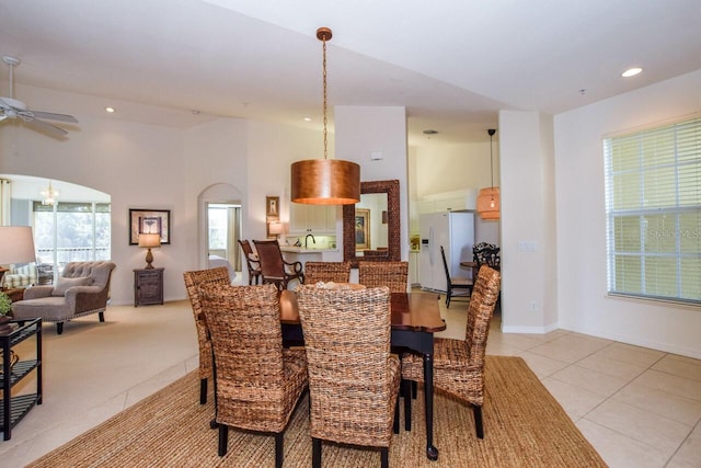 dining space featuring arched walkways, light tile patterned floors, recessed lighting, ceiling fan, and baseboards