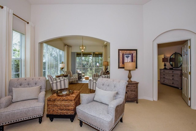 sitting room with arched walkways, light carpet, and a towering ceiling