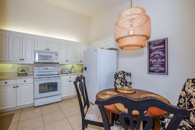 kitchen featuring light tile patterned floors, light countertops, white appliances, and white cabinets