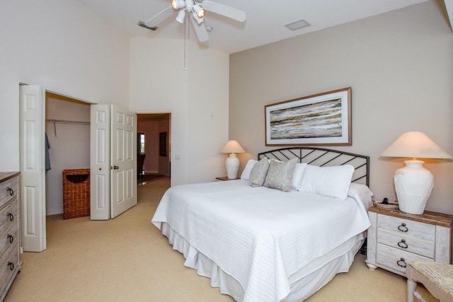 bedroom featuring a closet, a towering ceiling, a ceiling fan, and light colored carpet