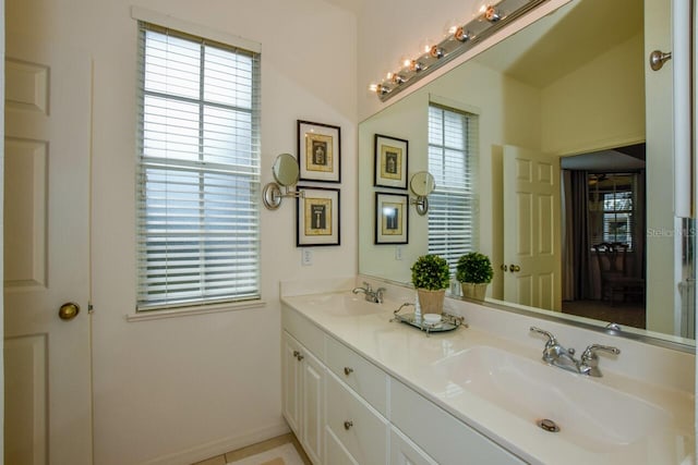 full bathroom featuring double vanity, baseboards, and a sink