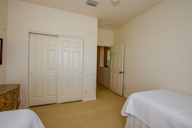 bedroom with a closet, visible vents, light carpet, and baseboards