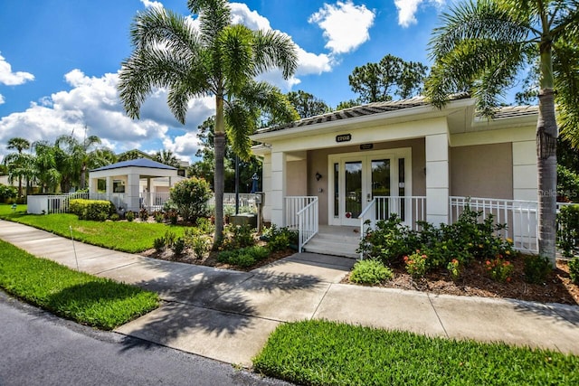 view of front of home featuring covered porch, fence, french doors, and stucco siding