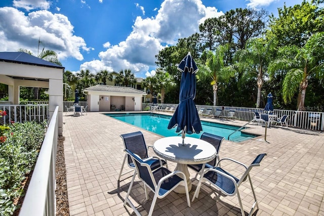 community pool with a patio area and fence