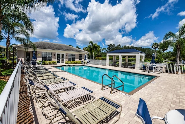 community pool featuring french doors, a patio area, and fence