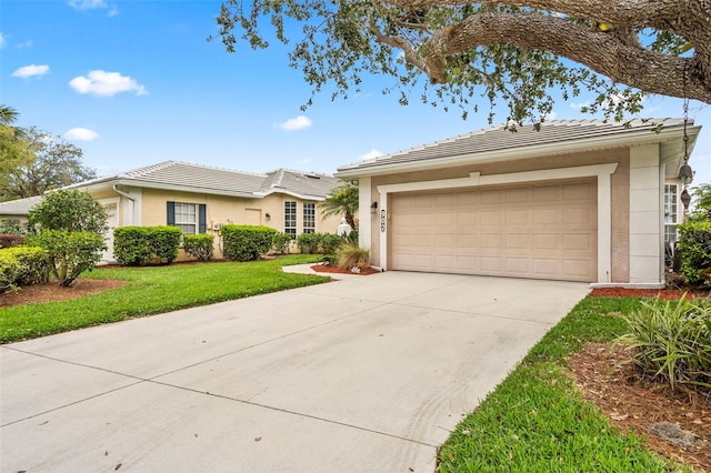 single story home with driveway, a tiled roof, a front lawn, and stucco siding