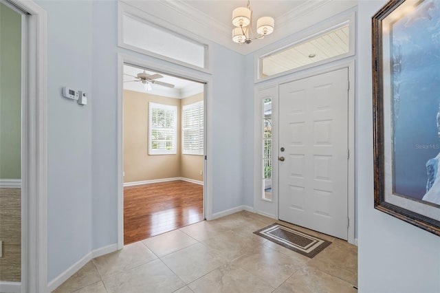 entrance foyer with a chandelier, crown molding, baseboards, and light tile patterned floors