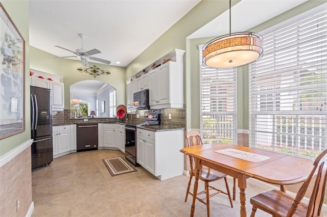 kitchen featuring arched walkways, stainless steel electric range oven, freestanding refrigerator, white cabinets, and dishwasher