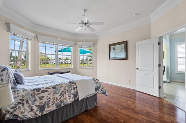 bedroom featuring a ceiling fan, crown molding, baseboards, and wood finished floors