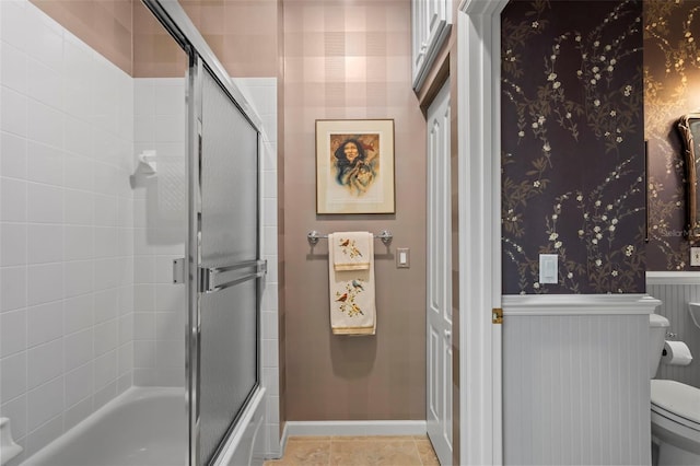 bathroom featuring wallpapered walls, baseboards, toilet, tile patterned floors, and combined bath / shower with glass door