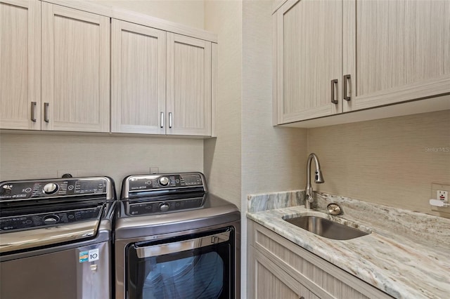 clothes washing area with cabinet space, separate washer and dryer, and a sink