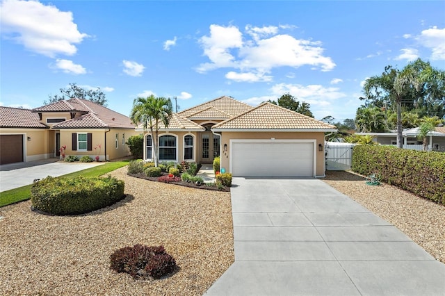 mediterranean / spanish home featuring a tile roof, stucco siding, concrete driveway, fence, and a garage