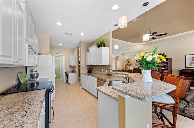 kitchen featuring arched walkways, a breakfast bar area, white microwave, a sink, and range with electric cooktop