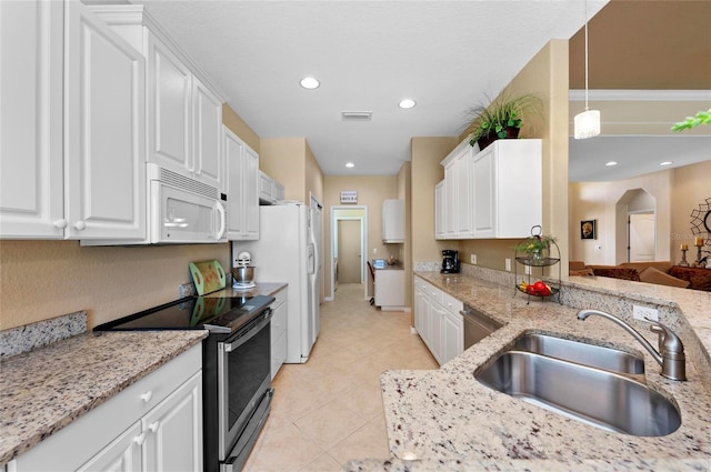 kitchen featuring stainless steel appliances, arched walkways, white cabinets, and a sink