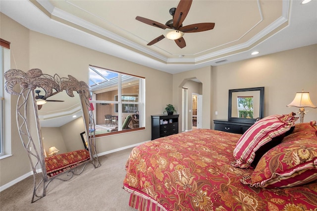 bedroom featuring arched walkways, a raised ceiling, ornamental molding, carpet flooring, and baseboards