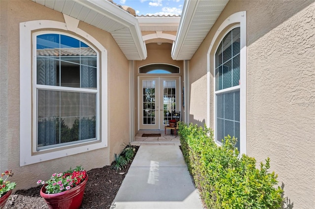 property entrance with a tiled roof, french doors, and stucco siding