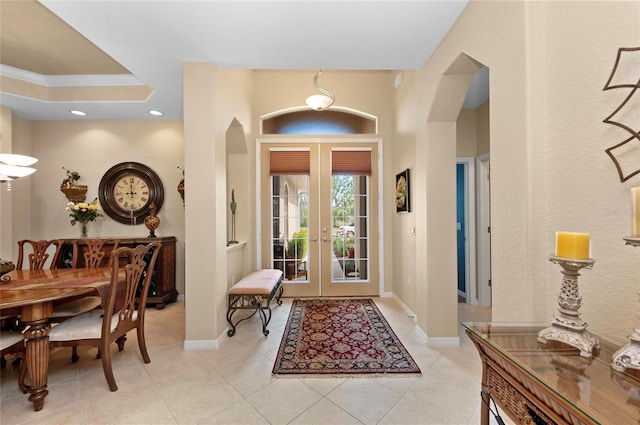 foyer entrance featuring light tile patterned floors, baseboards, arched walkways, and french doors