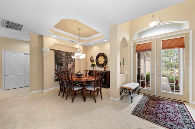 dining space featuring a tray ceiling, french doors, visible vents, and a notable chandelier