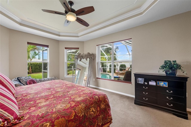 carpeted bedroom with baseboards, a tray ceiling, a ceiling fan, and crown molding