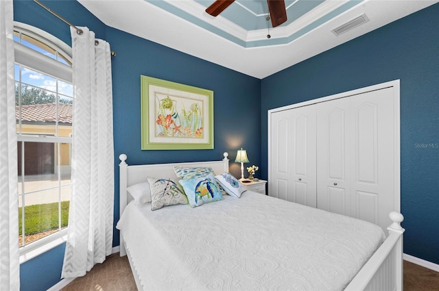 bedroom featuring carpet, a closet, visible vents, a raised ceiling, and baseboards