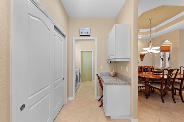 kitchen with light stone countertops, white cabinets, a notable chandelier, and light tile patterned flooring