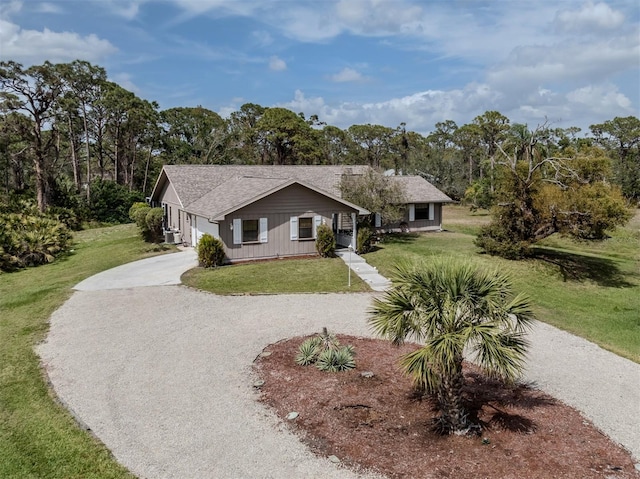 view of front of house with gravel driveway, a front yard, and a shingled roof