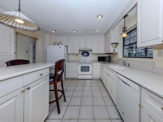 kitchen with light countertops, hanging light fixtures, white cabinets, white appliances, and a sink